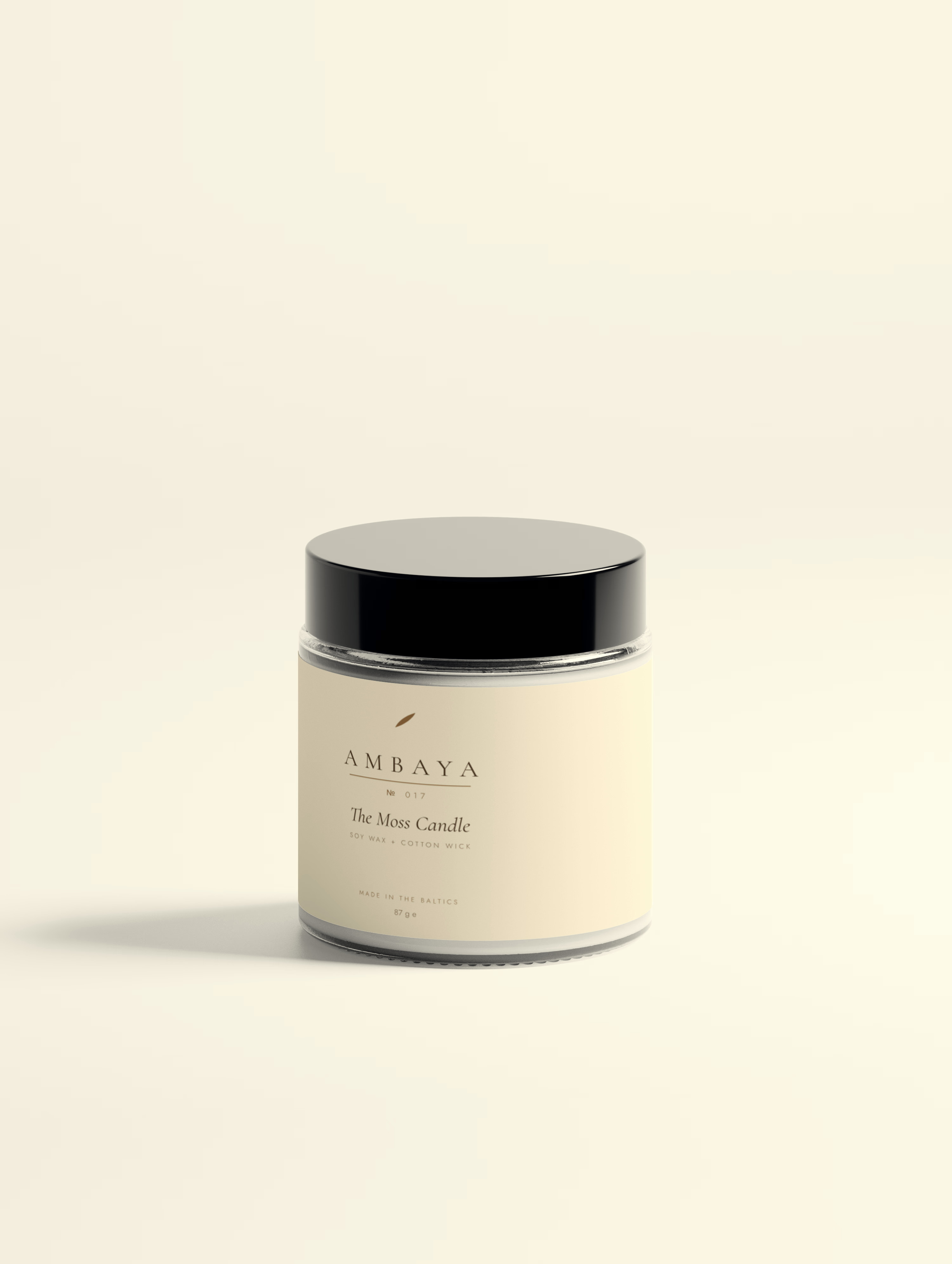 Cream-labelled glass jar of The Moss Candle, 87 g, with a black lid and the gold AMBAYA wordmark, on a pale cream background.