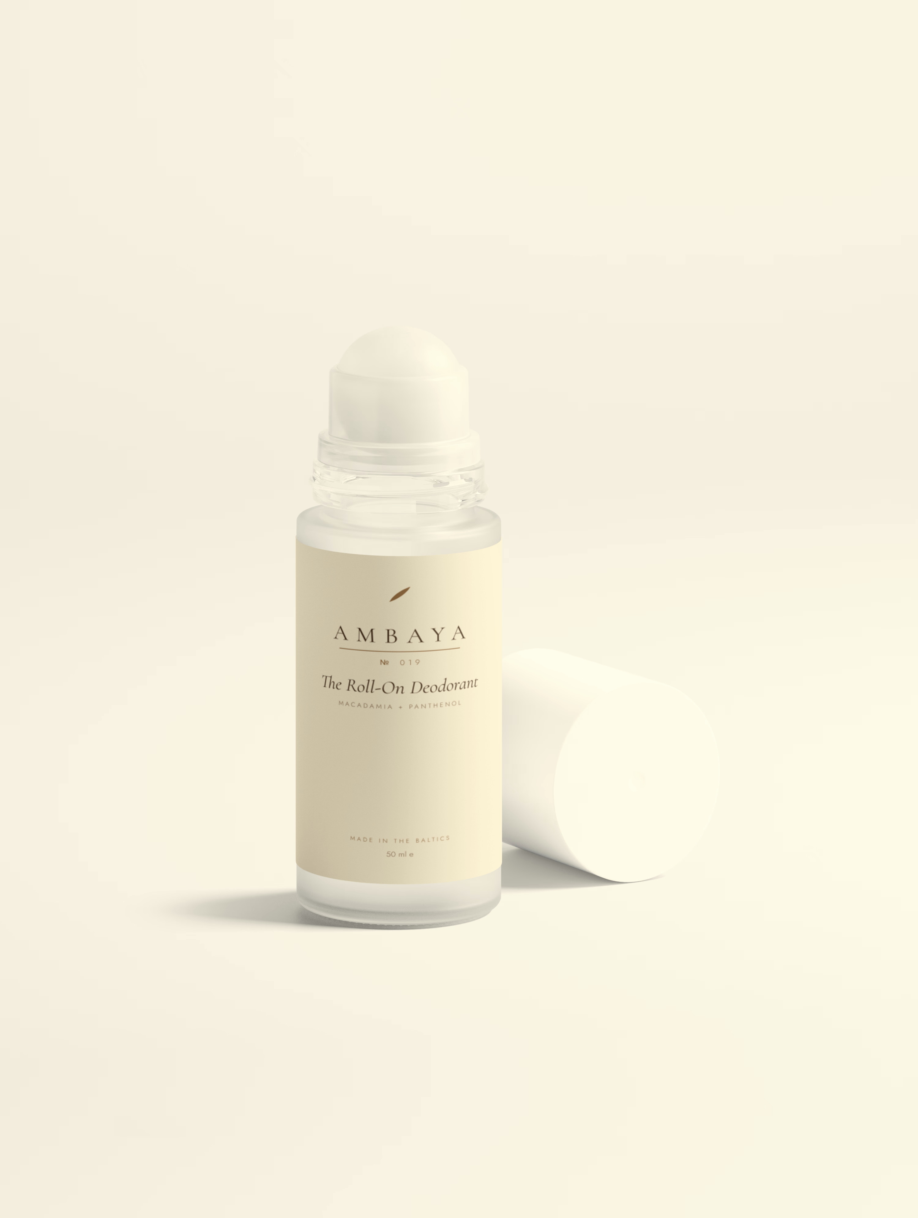 Frosted glass roll-on bottle of The Roll-On Deodorant, 50 ml, with a cream label and the gold AMBAYA wordmark, on a pale cream background.